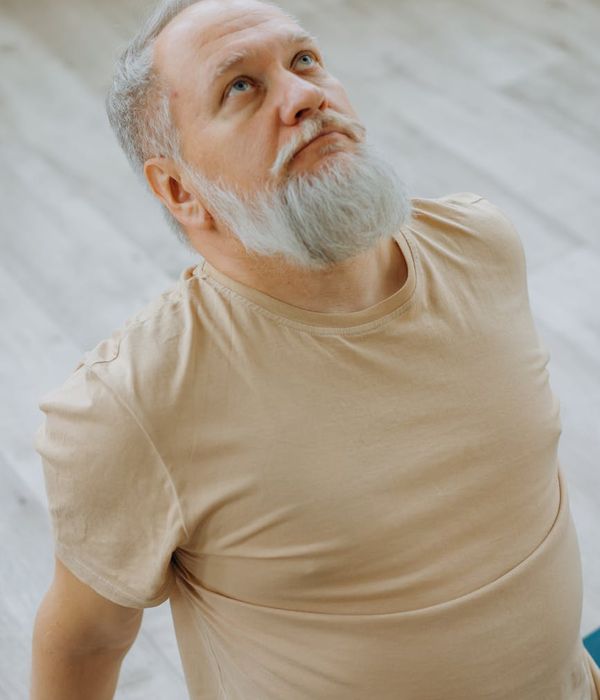 Man in a focused stretching pose against a calm background.